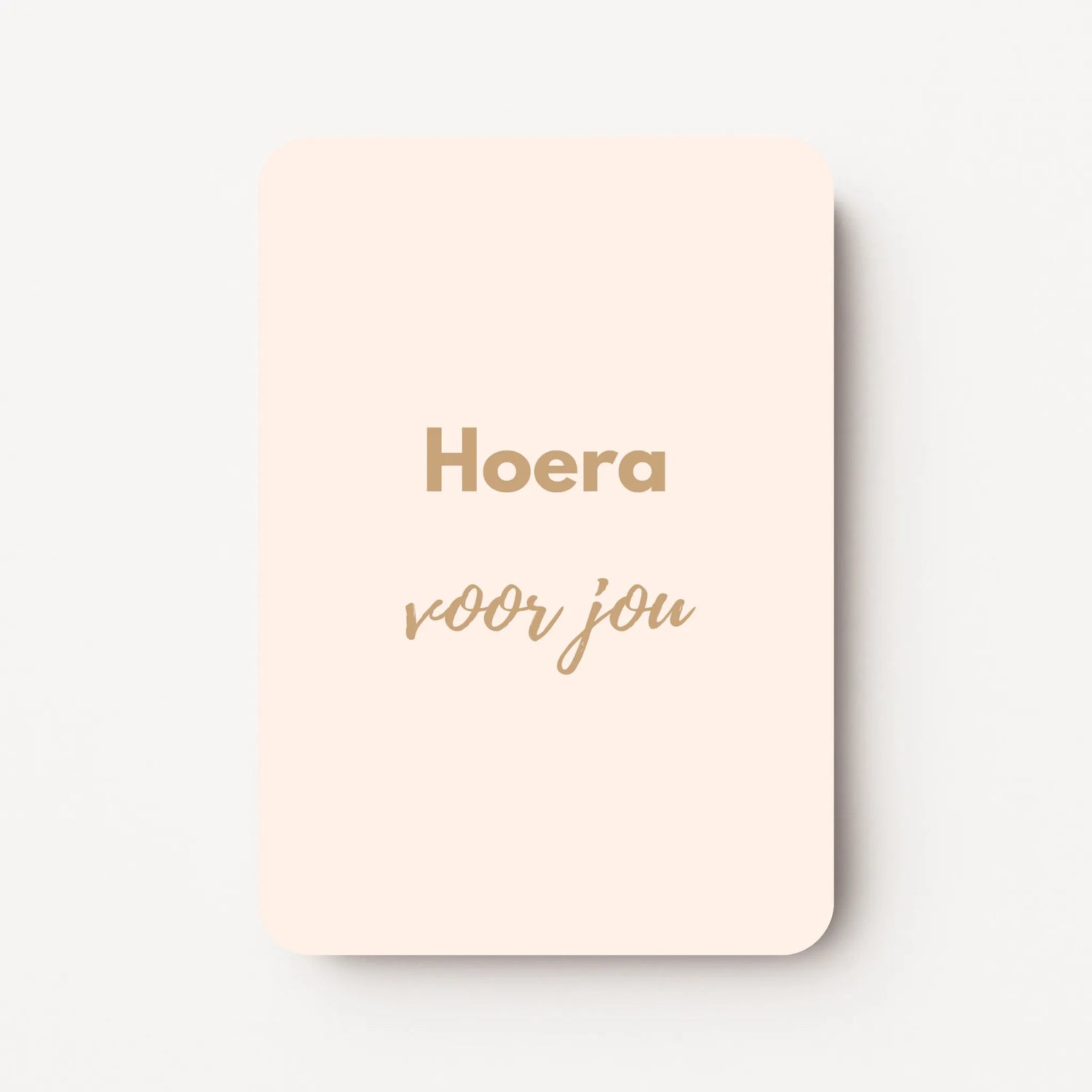 Staand minikaartje met goudbeige tekst ‘Hoera voor jou’, minimalistisch ontwerp op zachte roomkleurige achtergrond, flatlay op witte ondergrond.