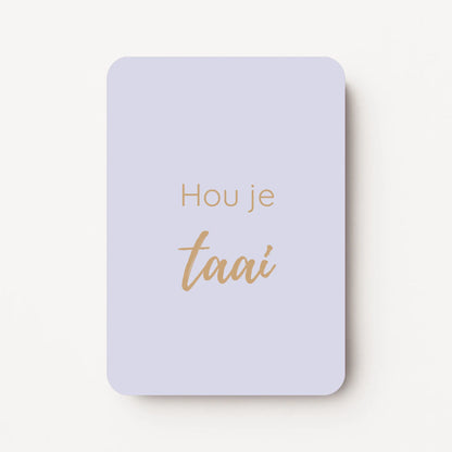 Staand minikaartje met tekst ‘Hou je taai’ in goudbeige letters, minimalistisch ontwerp op een zachte lila-grijze achtergrond, flatlay op witte ondergrond.