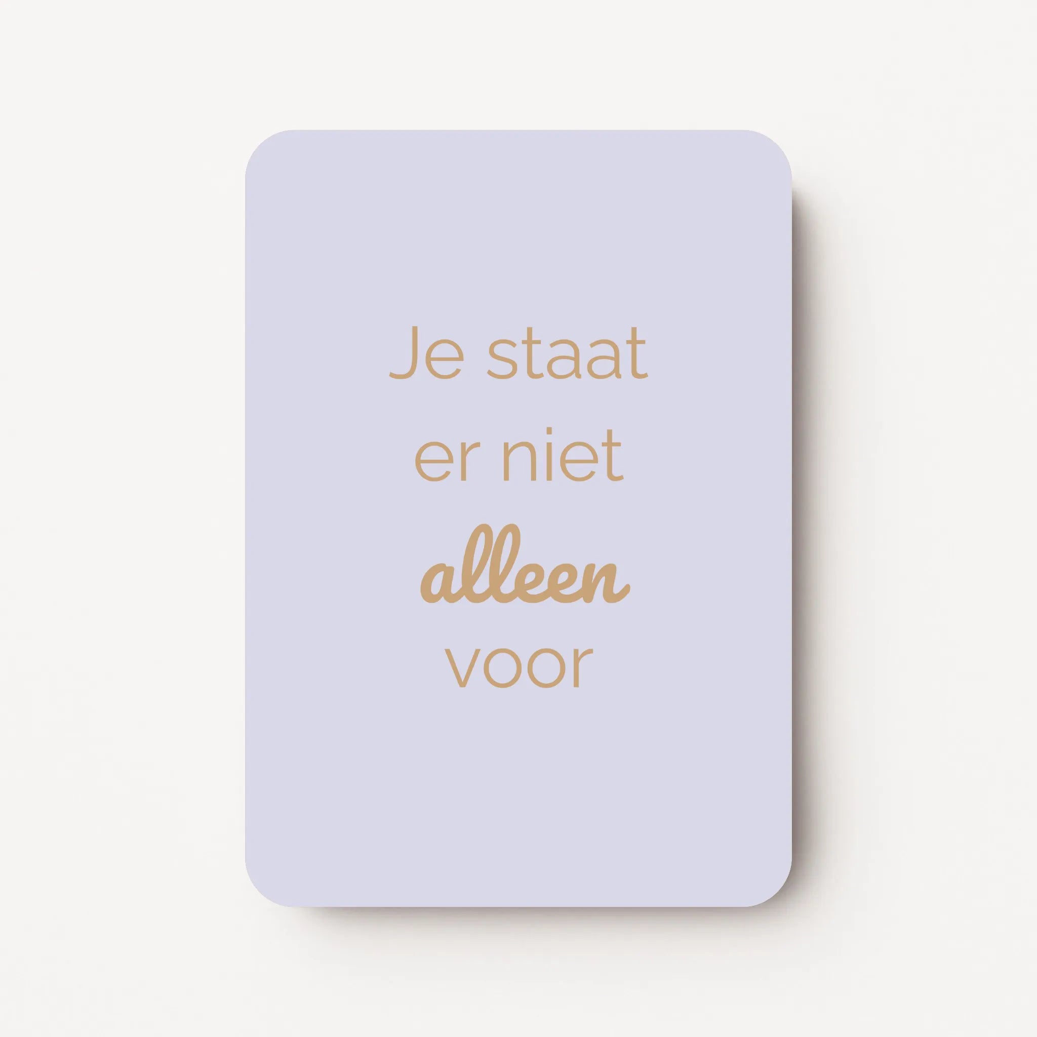 Staand minikaartje met goudbeige tekst ‘Je staat er niet alleen voor’, minimalistisch ontwerp op een zachte pastel-lila achtergrond, flatlay op witte ondergrond.