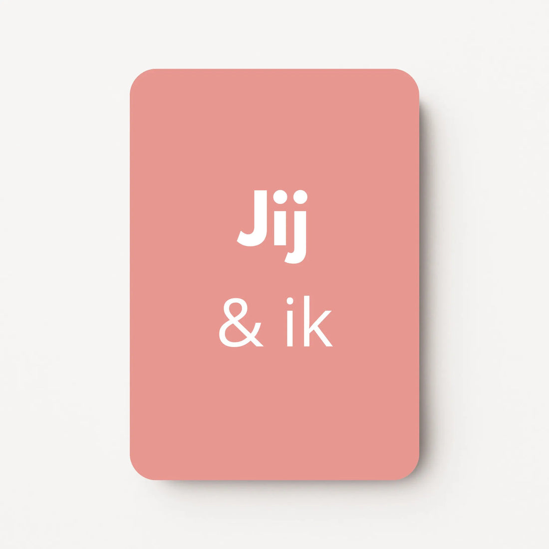 Staand minikaartje met witte tekst ‘Jij &amp; ik’, minimalistisch ontwerp op een warme oudroze achtergrond, flatlay op witte ondergrond.