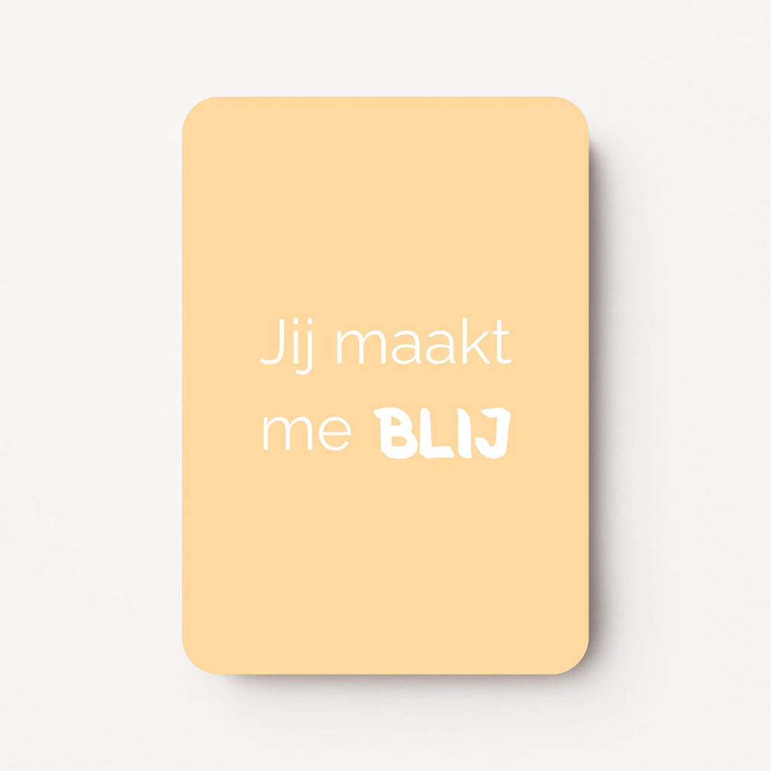 Staand minikaartje met witte tekst ‘Jij maakt me BLIJ’, minimalistisch ontwerp op een zachte abrikoos-gele achtergrond, flatlay op witte ondergrond.