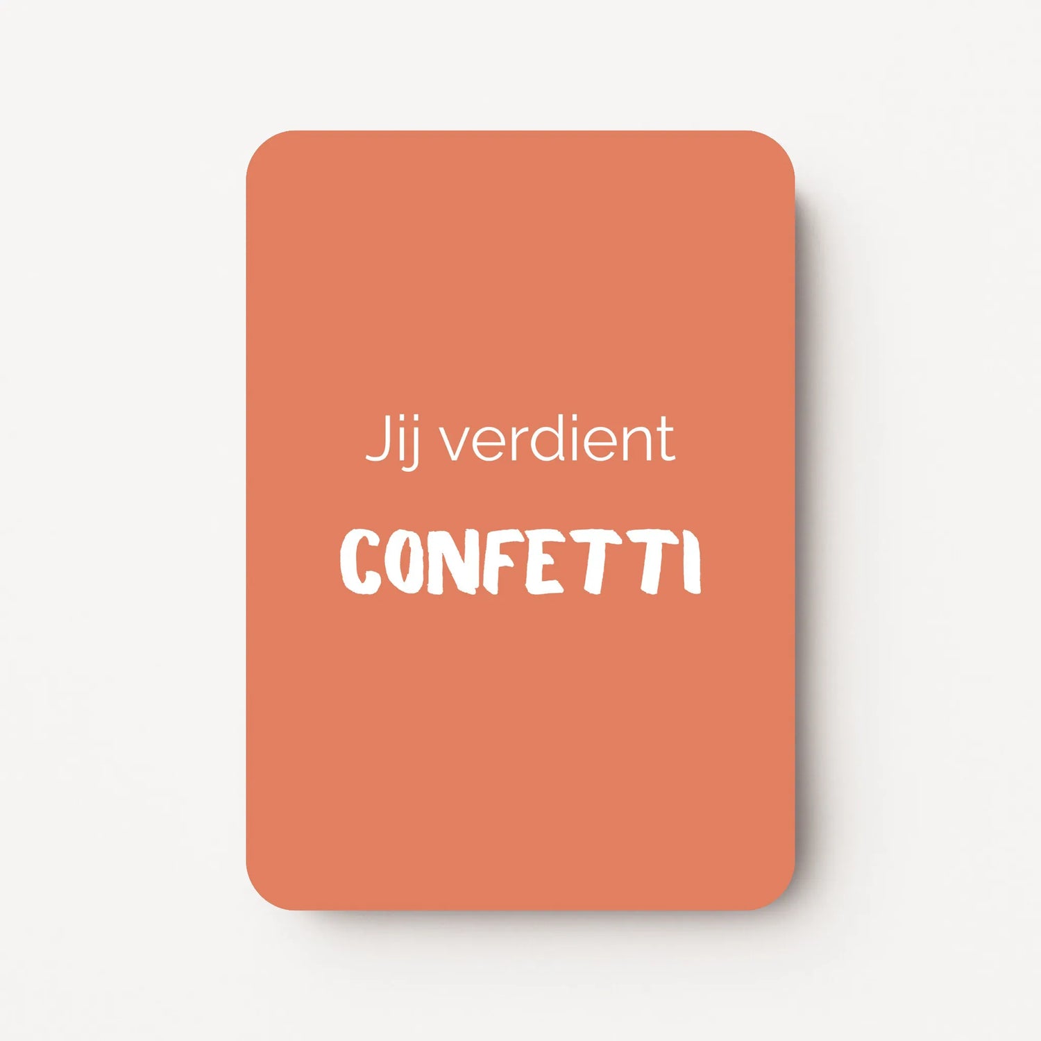 Staand minikaartje met witte tekst ‘Jij verdient CONFETTI’, minimalistisch ontwerp op warme perzikkleurige achtergrond, flatlay op witte ondergrond.