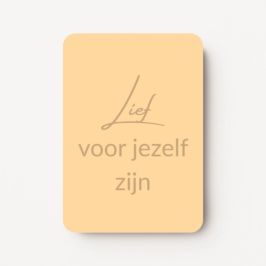 Staand minikaartje met tekst ‘Lief voor jezelf zijn’ in goudbeige letters, minimalistisch ontwerp op een zachte perzikgele achtergrond, flatlay op witte ondergrond.