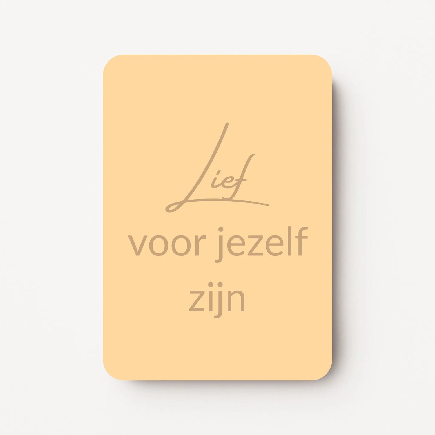 Staand minikaartje met tekst ‘Lief voor jezelf zijn’ in goudbeige letters, minimalistisch ontwerp op een zachte perzikgele achtergrond, flatlay op witte ondergrond.