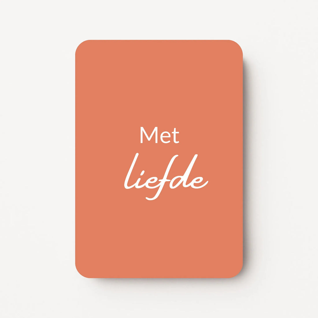 Staand minikaartje met witte tekst ‘Met liefde’, minimalistisch ontwerp op een warme koraalroze achtergrond, flatlay op witte ondergrond.