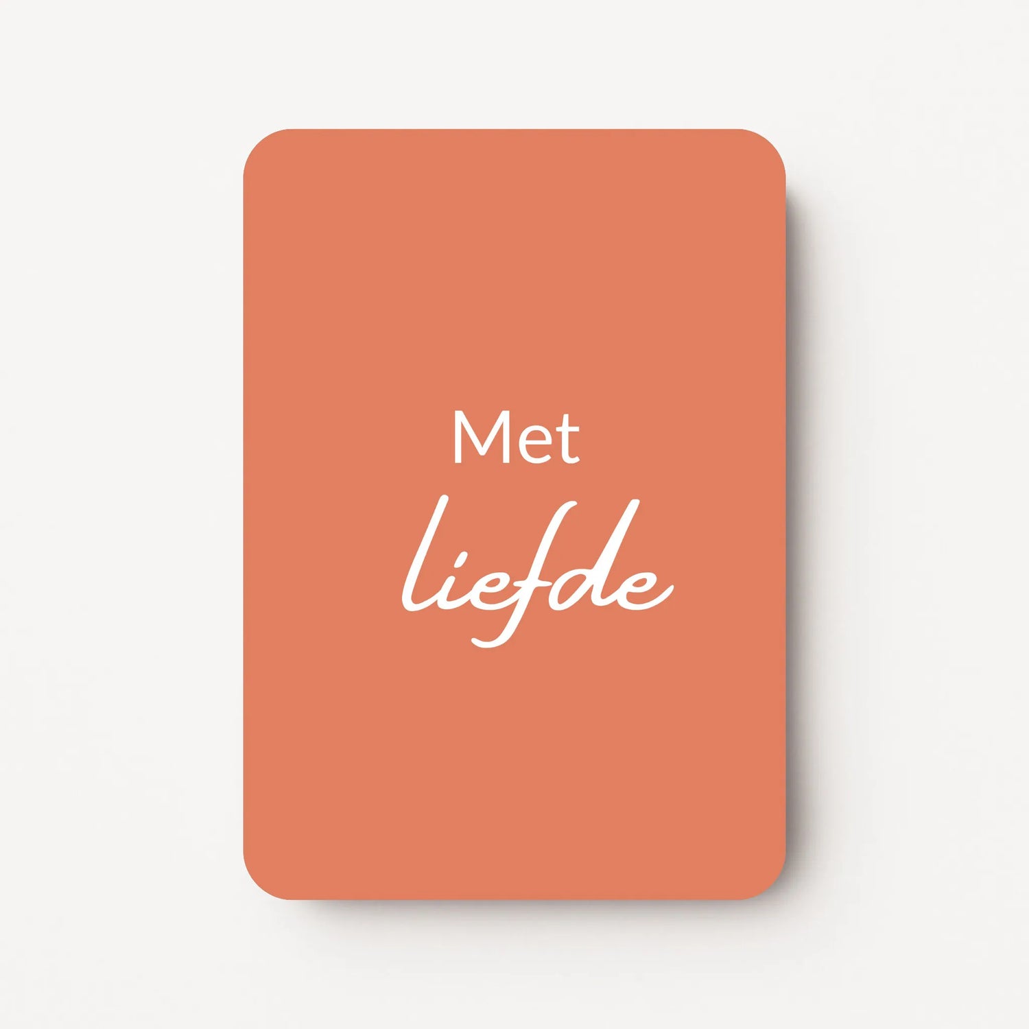 Staand minikaartje met witte tekst ‘Met liefde’, minimalistisch ontwerp op een warme koraalroze achtergrond, flatlay op witte ondergrond.