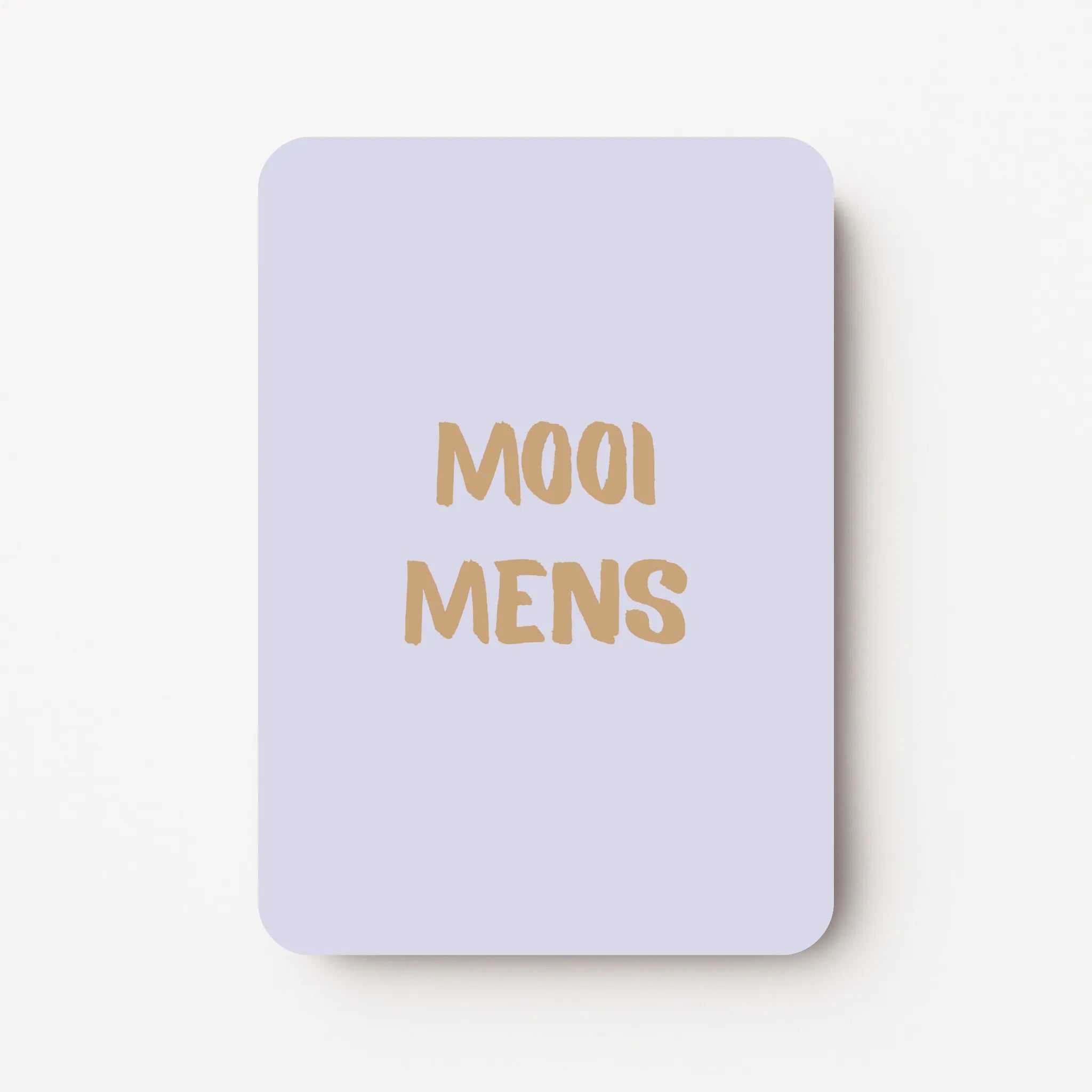 Staand minikaartje met goudbeige tekst ‘MOOI MENS’, minimalistisch ontwerp op een zachte koelgrijze achtergrond, flatlay op witte ondergrond.
