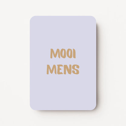 Staand minikaartje met goudbeige tekst ‘MOOI MENS’, minimalistisch ontwerp op een zachte koelgrijze achtergrond, flatlay op witte ondergrond.
