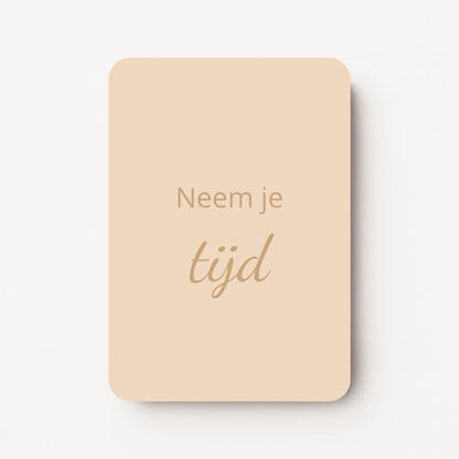 Staand minikaartje met tekst ‘Neem je tijd’ in goudbeige letters, minimalistisch ontwerp op een warme zandbeige achtergrond, flatlay op witte ondergrond.