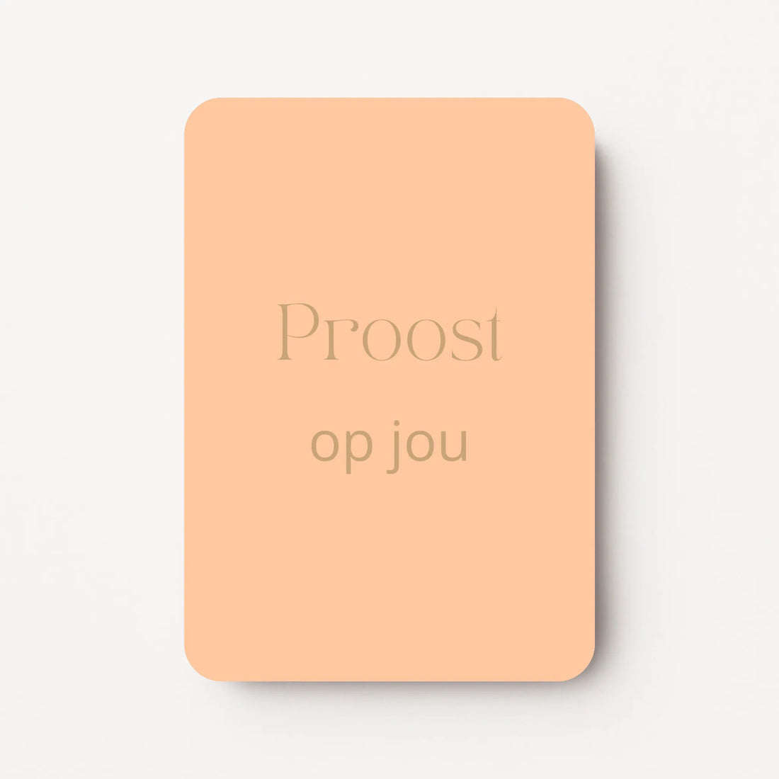 Staand minikaartje met goudbeige tekst ‘Proost op jou’, minimalistisch ontwerp op zachte perzikkleurige achtergrond, flatlay op witte ondergrond.
