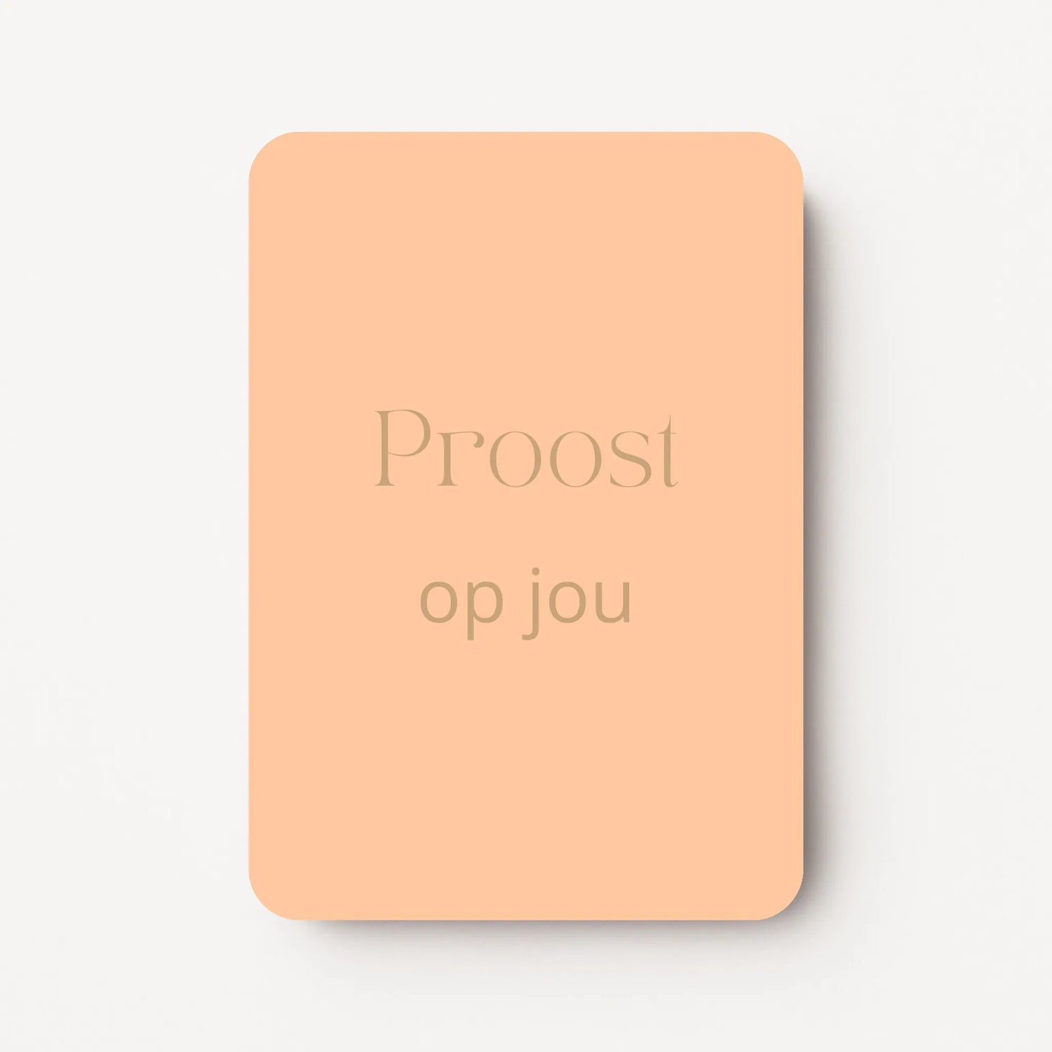 Staand minikaartje met goudbeige tekst ‘Proost op jou’, minimalistisch ontwerp op zachte perzikkleurige achtergrond, flatlay op witte ondergrond.