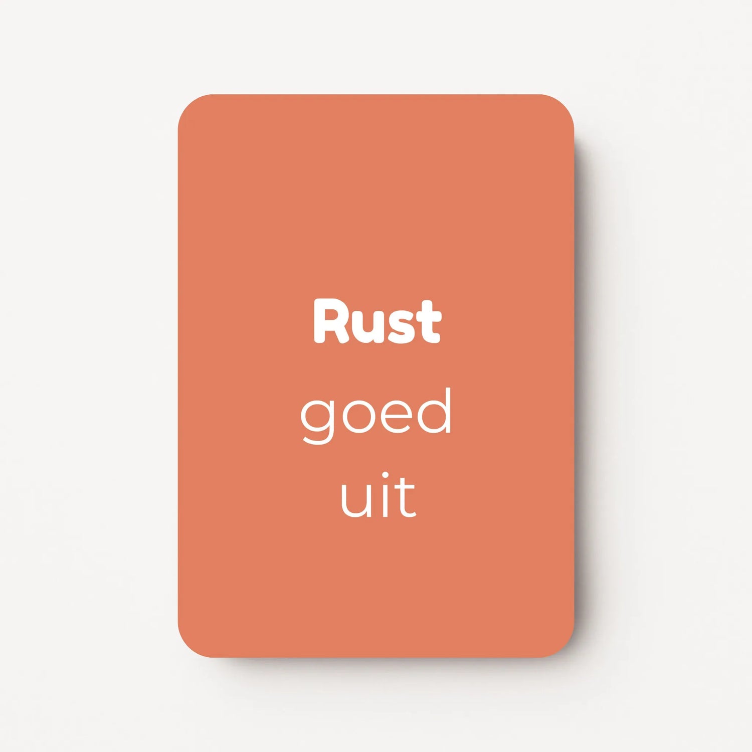 Staand minikaartje met tekst ‘Rust goed uit’ in witte letters, minimalistisch ontwerp op warme koraalroze achtergrond, flatlay op witte ondergrond.