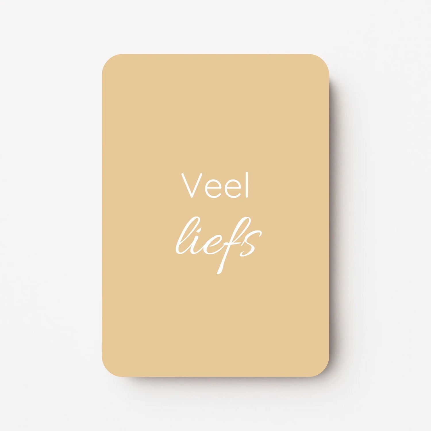 Staand minikaartje met tekst ‘Veel liefs’ in witte letters, minimalistisch ontwerp op zachte honinggele achtergrond, flatlay op witte ondergrond.