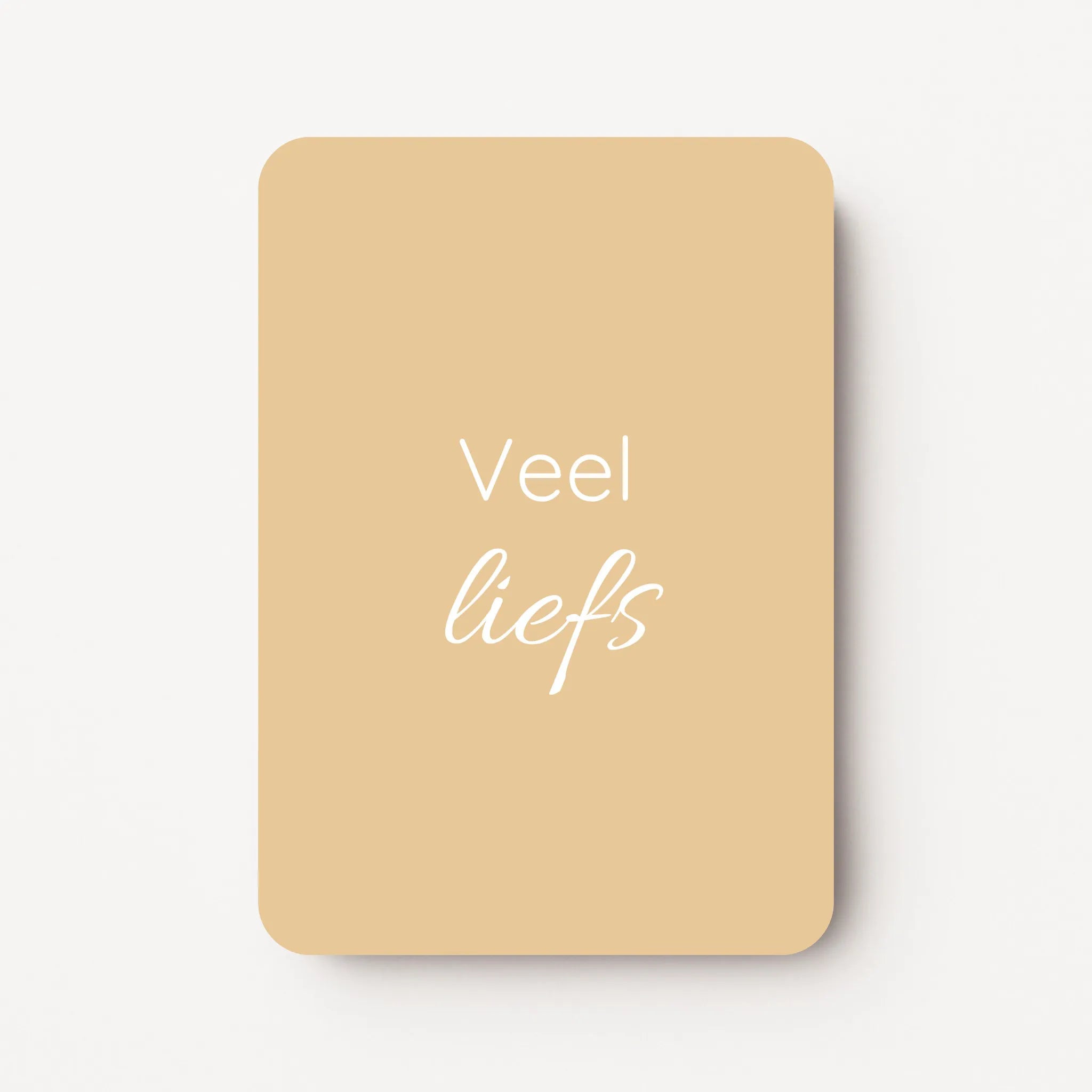 Staand minikaartje met tekst ‘Veel liefs’ in witte letters, minimalistisch ontwerp op zachte honinggele achtergrond, flatlay op witte ondergrond.