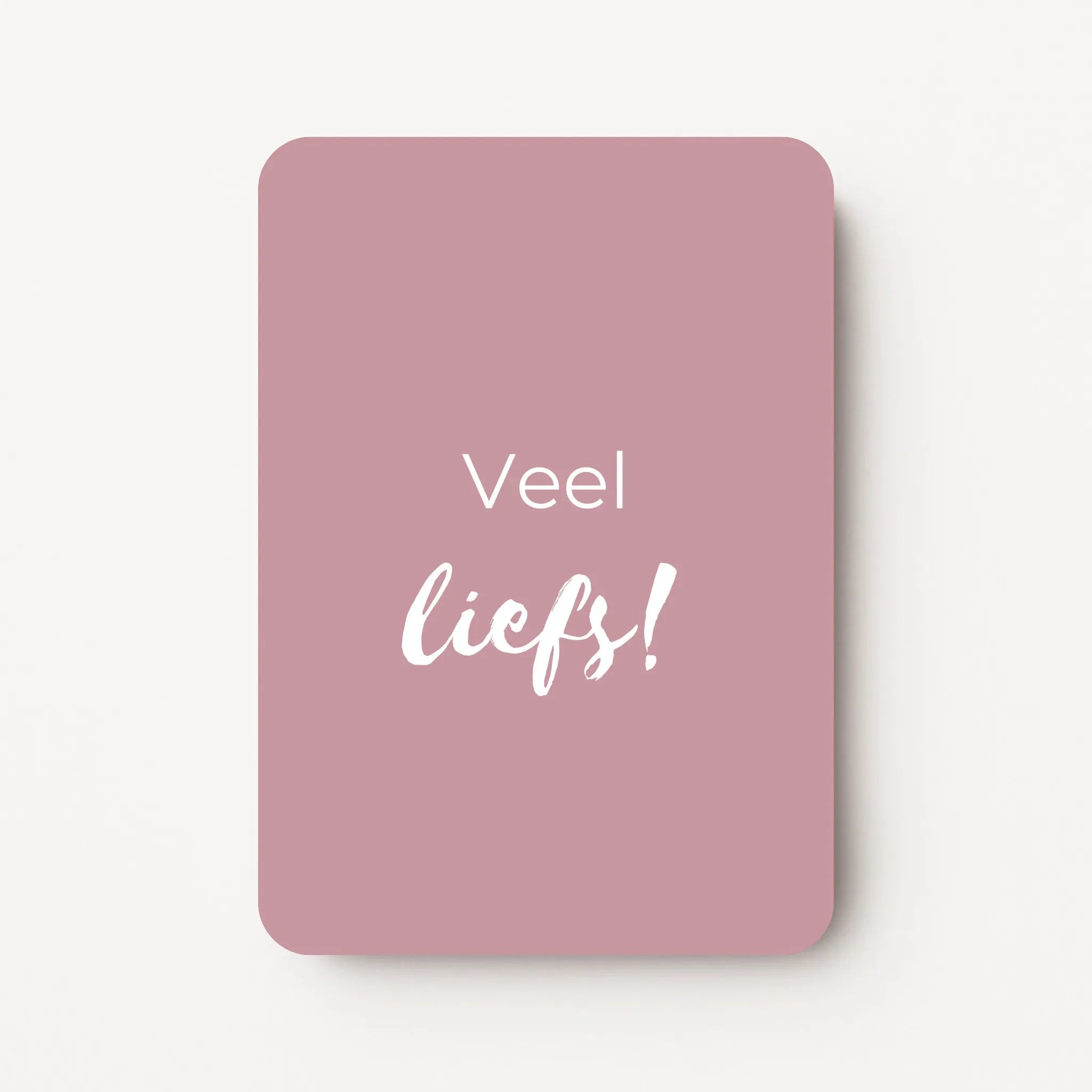Staand minikaartje met witte tekst ‘Veel liefs!’, minimalistisch ontwerp op een zachte mauve achtergrond, flatlay op witte ondergrond.