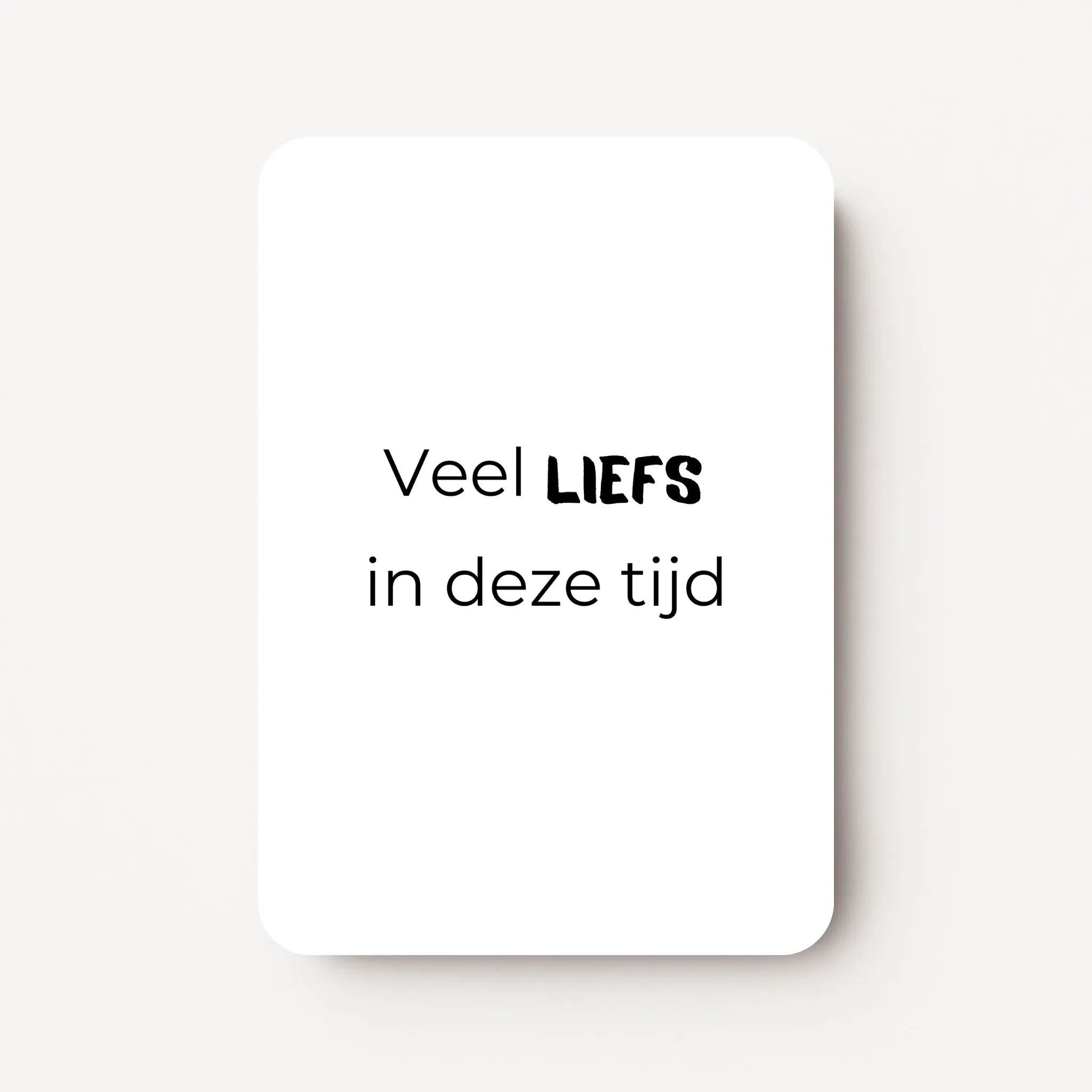 Staand minikaartje met zwarte tekst ‘Veel LIEFS in deze tijd’, minimalistisch ontwerp op witte achtergrond, flatlay op witte ondergrond.