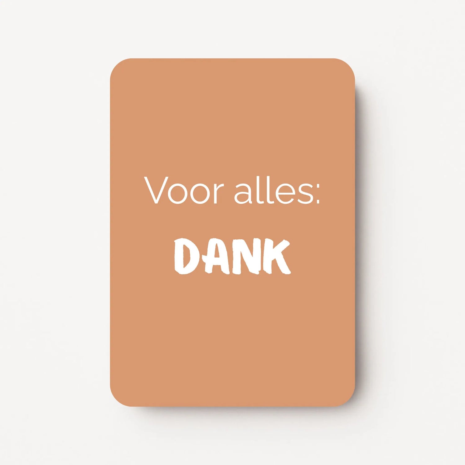 Staand minikaartje met witte tekst ‘Voor alles: DANK’ op warme caramelkleurige achtergrond, minimalistisch ontwerp, flatlay op witte ondergrond.