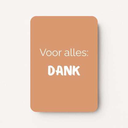 Staand minikaartje met witte tekst ‘Voor alles: DANK’ op warme caramelkleurige achtergrond, minimalistisch ontwerp, flatlay op witte ondergrond.