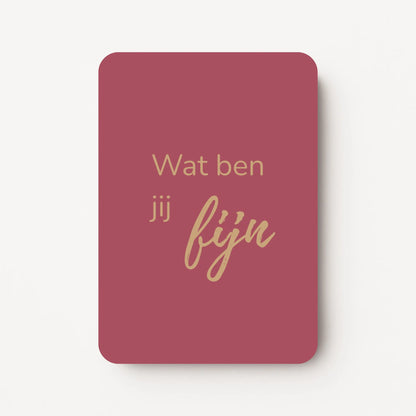 Staand minikaartje met tekst ‘Wat ben jij fijn’ in goudbeige letters, minimalistisch ontwerp op diepe roodoranje achtergrond, flatlay op witte ondergrond.