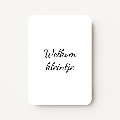 Staand minikaartje met zwarte tekst ‘Welkom kleintje’, minimalistisch ontwerp op witte achtergrond, flatlay op witte ondergrond.