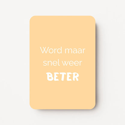Staand minikaartje met tekst ‘Word maar snel weer BETER’ in witte letters, minimalistisch ontwerp op zachte abrikoos-gele achtergrond, flatlay op witte ondergrond.