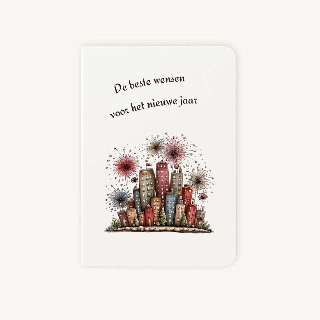 Staande dubbelgevouwen nieuwjaarskaart met afgeronde hoekjes en aquarelillustratie van kleurrijke flatgebouwen met sprankelend vuurwerk, omlijst door sierlijke tekst ‘De beste wensen voor het nieuwe jaar’, flatlay op lichte achtergrond.