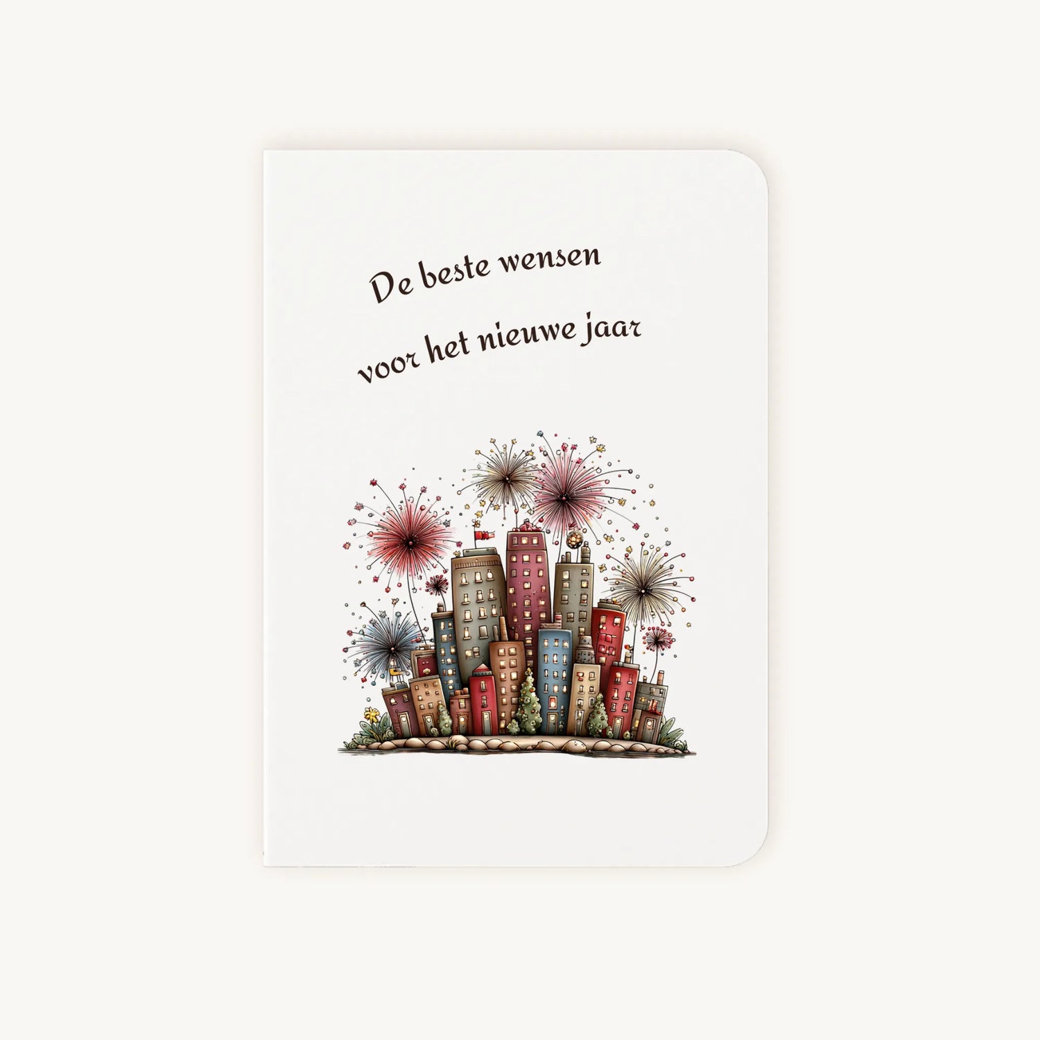 Staande dubbelgevouwen nieuwjaarskaart met afgeronde hoekjes en aquarelillustratie van kleurrijke flatgebouwen met sprankelend vuurwerk, omlijst door sierlijke tekst ‘De beste wensen voor het nieuwe jaar’, flatlay op lichte achtergrond.