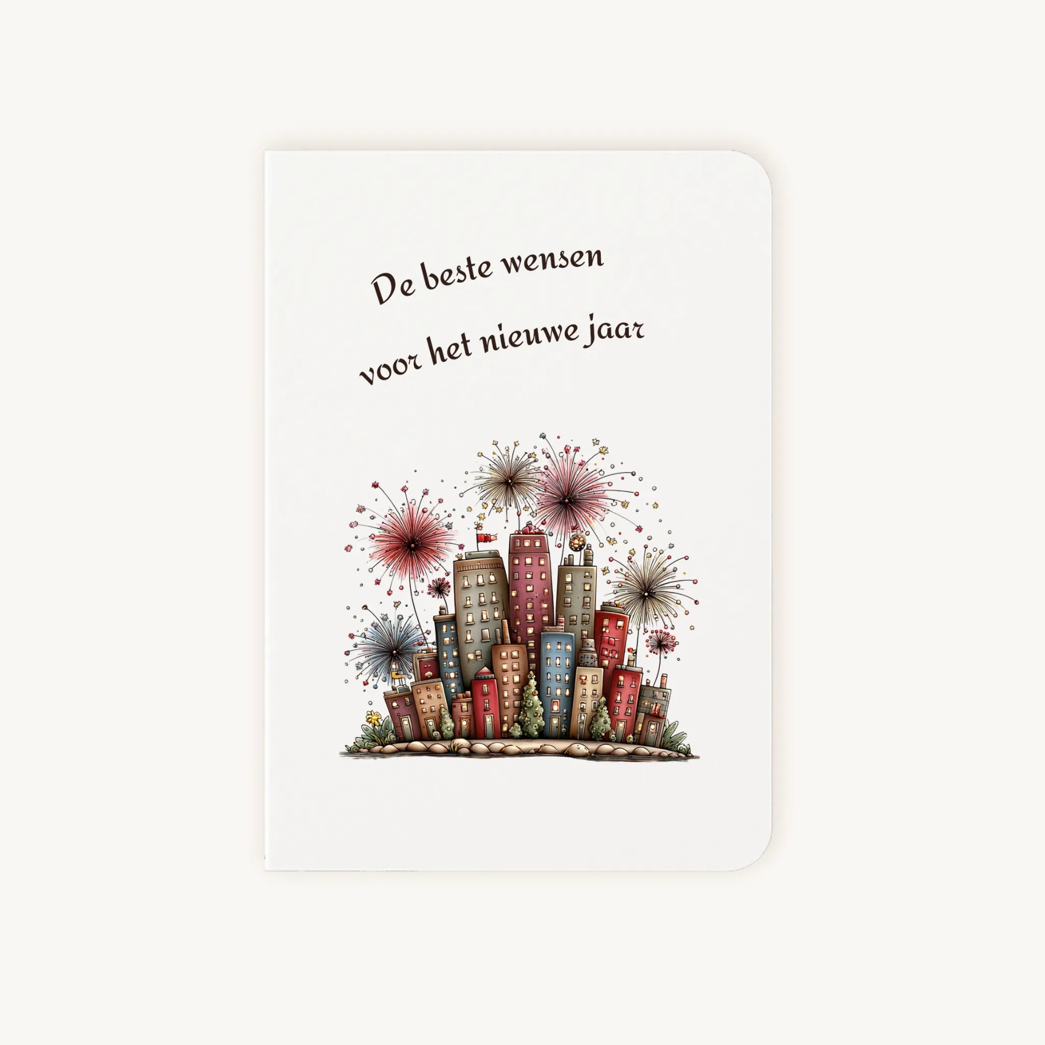 Staande dubbelgevouwen nieuwjaarskaart met afgeronde hoekjes en aquarelillustratie van kleurrijke flatgebouwen met sprankelend vuurwerk, omlijst door sierlijke tekst ‘De beste wensen voor het nieuwe jaar’, flatlay op lichte achtergrond.
