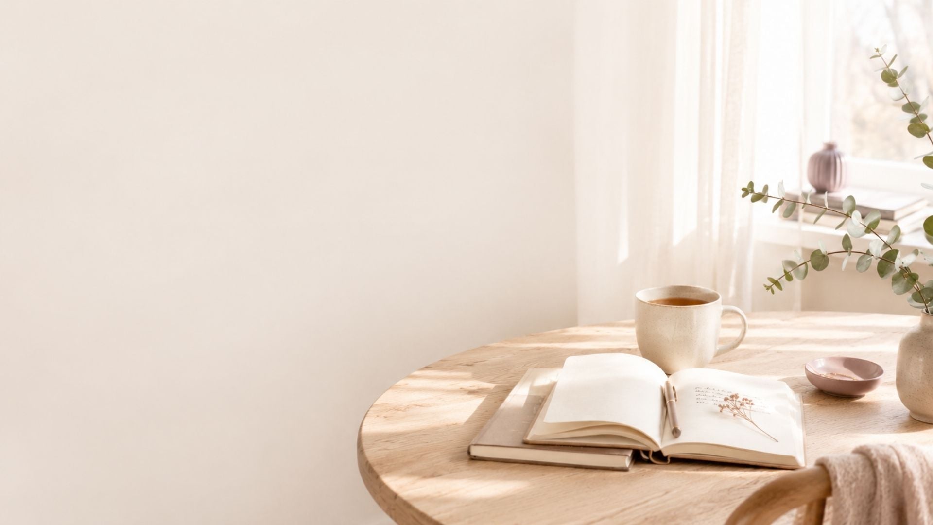Warme Scandinavische zithoek met een houten tafel, een kop thee, een open notitieboek en zacht daglicht in een rustige, huiselijke omgeving.