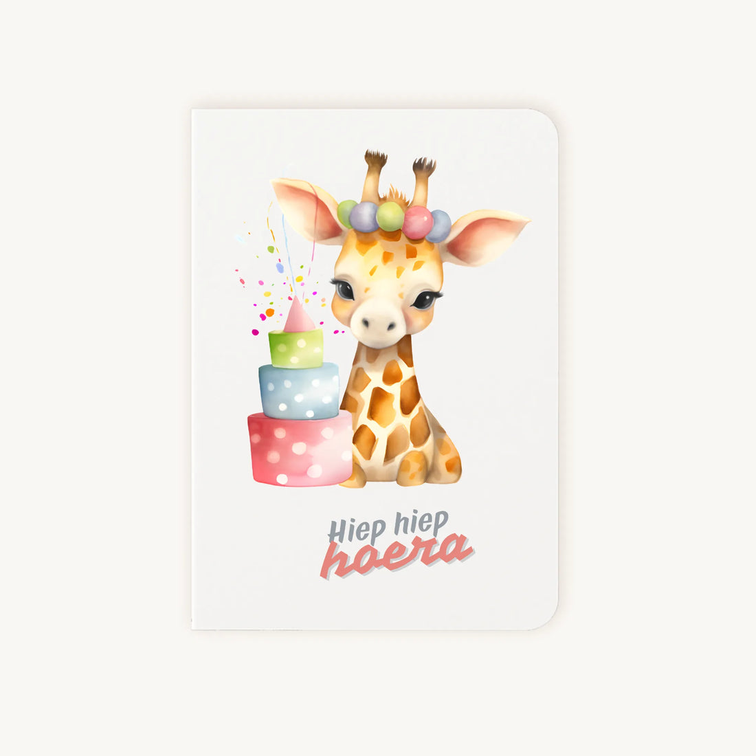 Staande dubbelgevouwen verjaardagskaart met schattige giraf met feesthoedje en kleurrijke verjaardagstaart, met tekst Hiep hiep hoera, flatlay op lichte achtergrond.