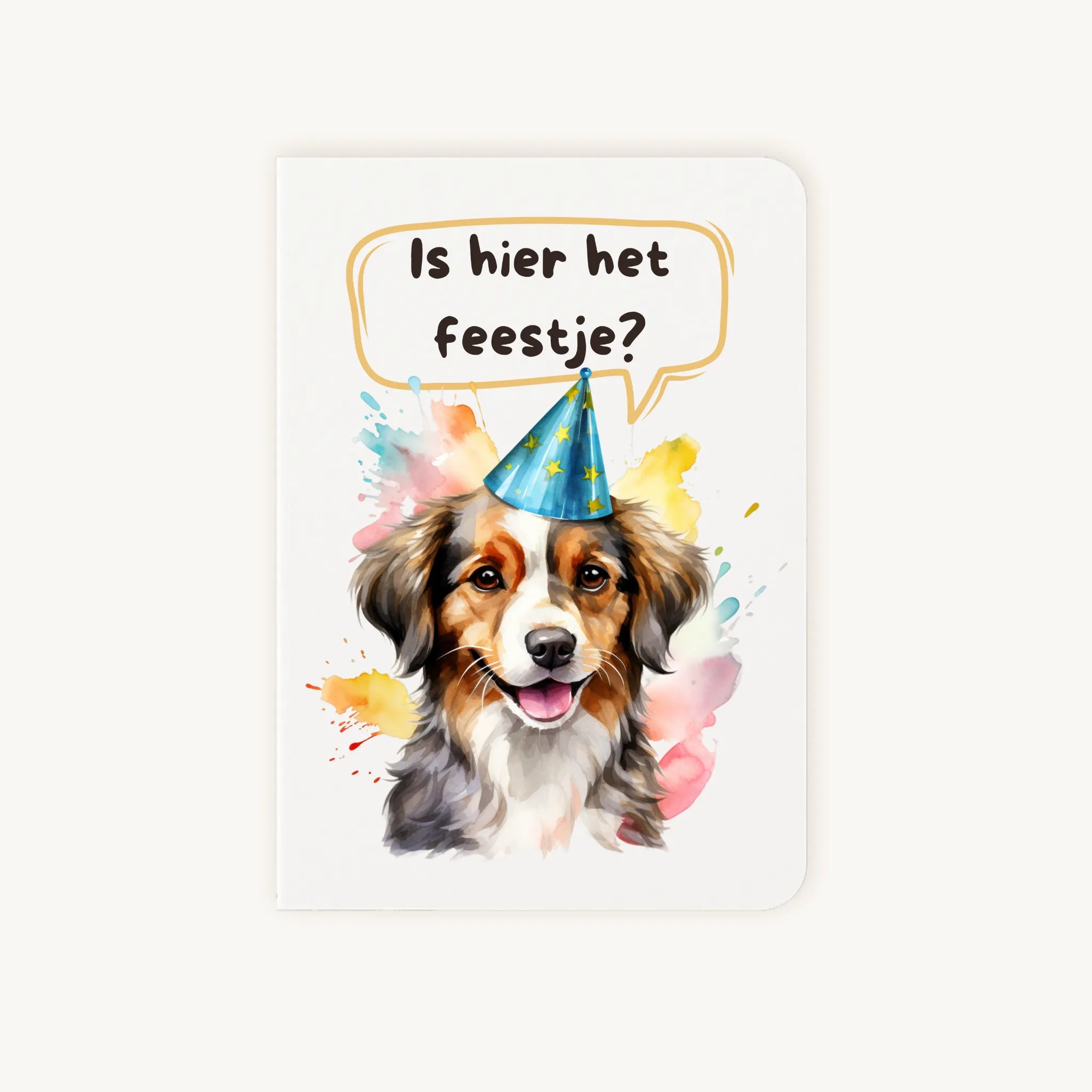 Staande dubbelgevouwen verjaardagskaart met vrolijke hond met feesthoedje en tekst Is hier het feestje?, flatlay op lichte achtergrond.