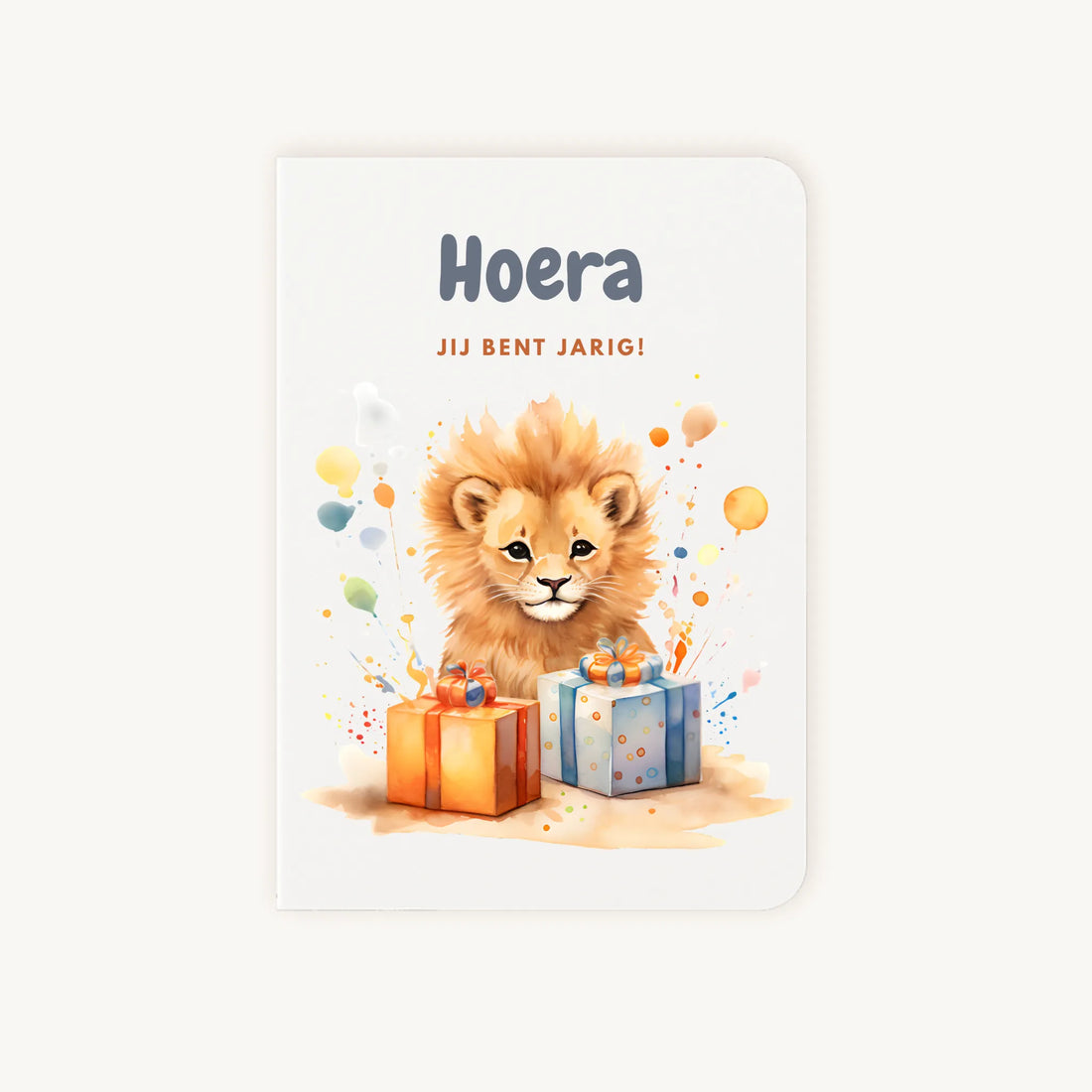 Staande dubbelgevouwen verjaardagskaart met schattige leeuwenwelp tussen kleurrijke cadeautjes en confetti, met tekst Hoera jij bent jarig, flatlay op lichte achtergrond.