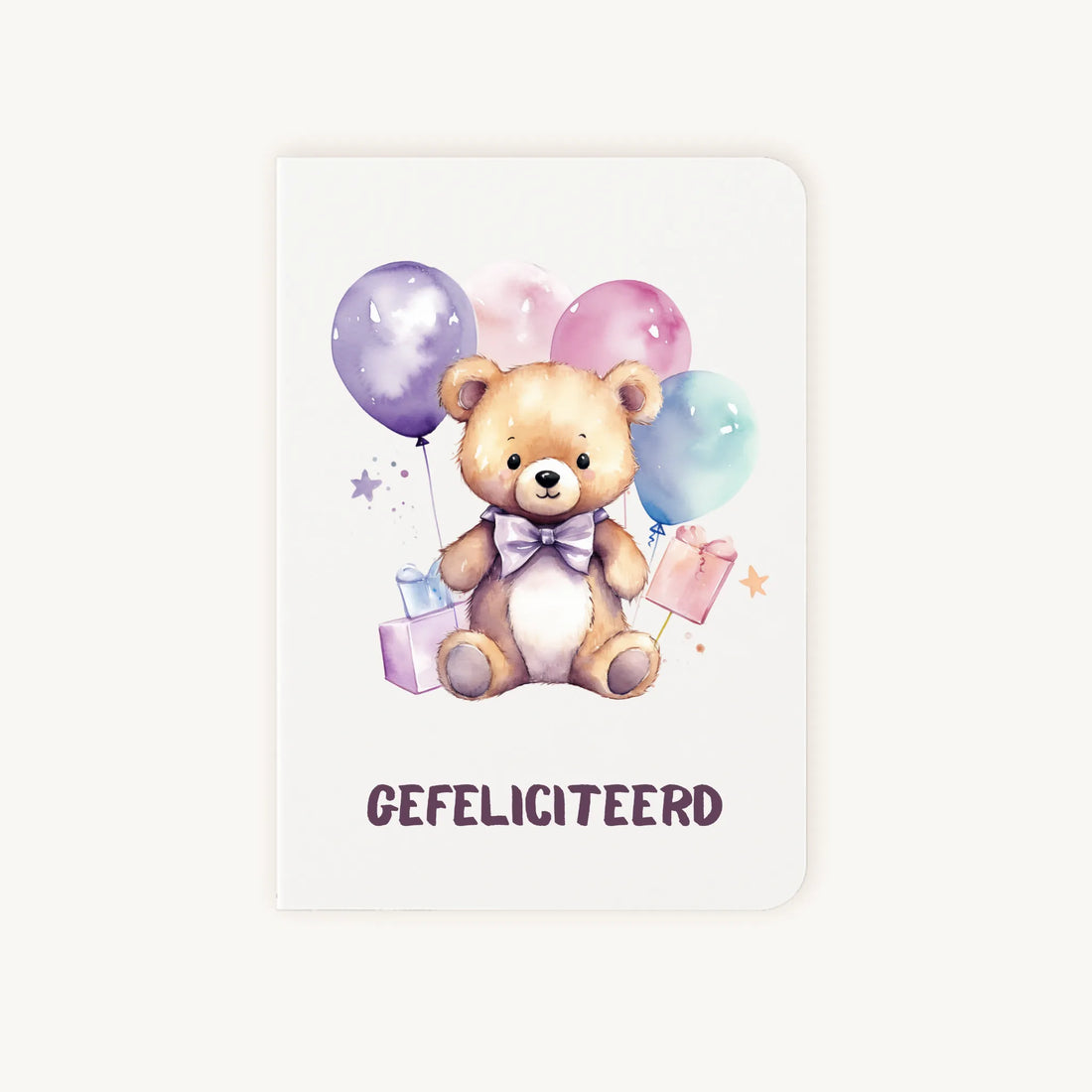 Staande dubbelgevouwen verjaardagskaart met lieve teddybeer met strik, ballonnen en cadeautjes, met tekst Gefeliciteerd, flatlay op lichte achtergrond.