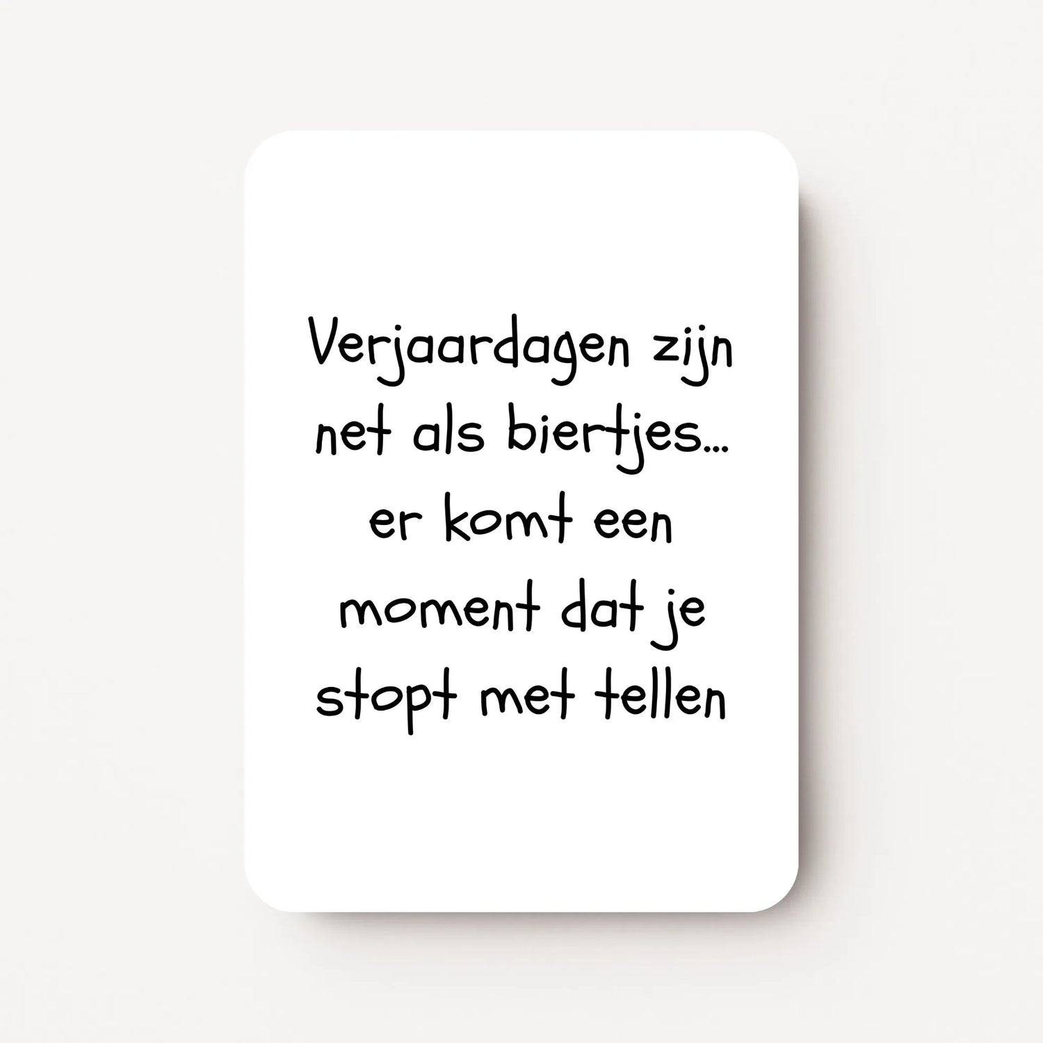 Staande verjaardagskaart voor mannen met zwarte tekst ‘Verjaardagen zijn net als biertjes... er komt een moment dat je stopt met tellen’, flatlay op witte ondergrond.