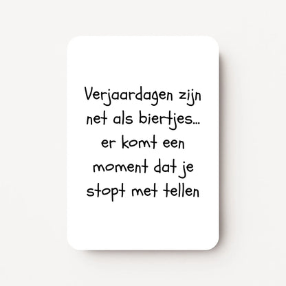 Staande verjaardagskaart voor mannen met zwarte tekst ‘Verjaardagen zijn net als biertjes... er komt een moment dat je stopt met tellen’, flatlay op witte ondergrond.