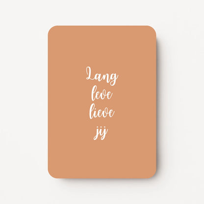 Staande verjaardagskaart voor een man met witte tekst ‘Lang leve lieve jij’ op een zandkleurige achtergrond, rustig en modern ontwerp, flatlay op witte ondergrond.