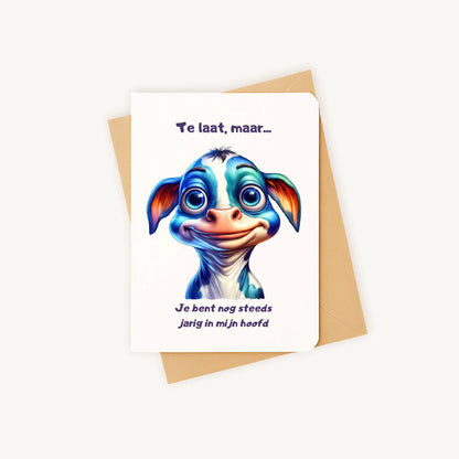 Staande verjaardagskaart met illustratie van blauwe ogen-koe op kraftenvelop.