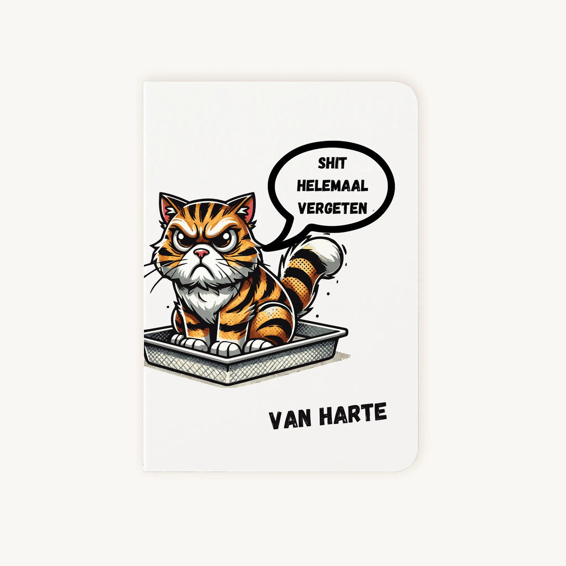 Staande dubbelgevouwen verjaardagskaart met chagrijnige getekende tijgerkat in een kattenbak, kleurrijke humoristische illustratie en tekst Shit helemaal vergeten van harte, flatlay op lichte achtergrond.