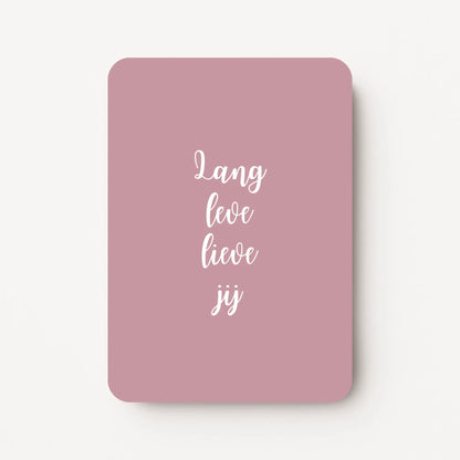 Staande verjaardagskaart voor een vrouw met witte tekst ‘Lang leve lieve jij’ op een zachte oudroze achtergrond, flatlay op witte ondergrond.