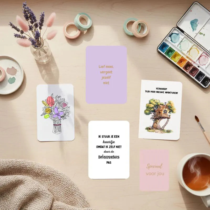 Wenskaarten collectie staand op houten bureau met afgeronde hoeken, omringd door droogbloemen en creatieve materialen