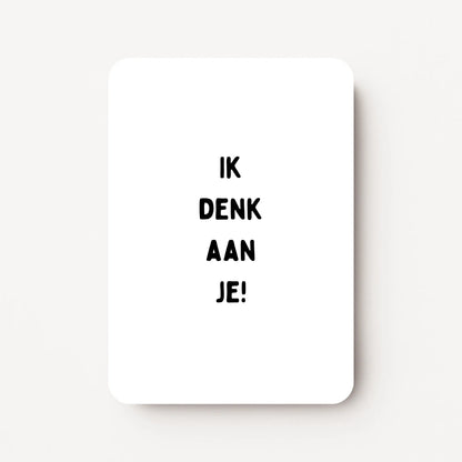 Staande zomaarkaart met zwarte tekst ‘Denk aan je’, minimalistisch ontwerp op witte achtergrond, flatlay op witte ondergrond.