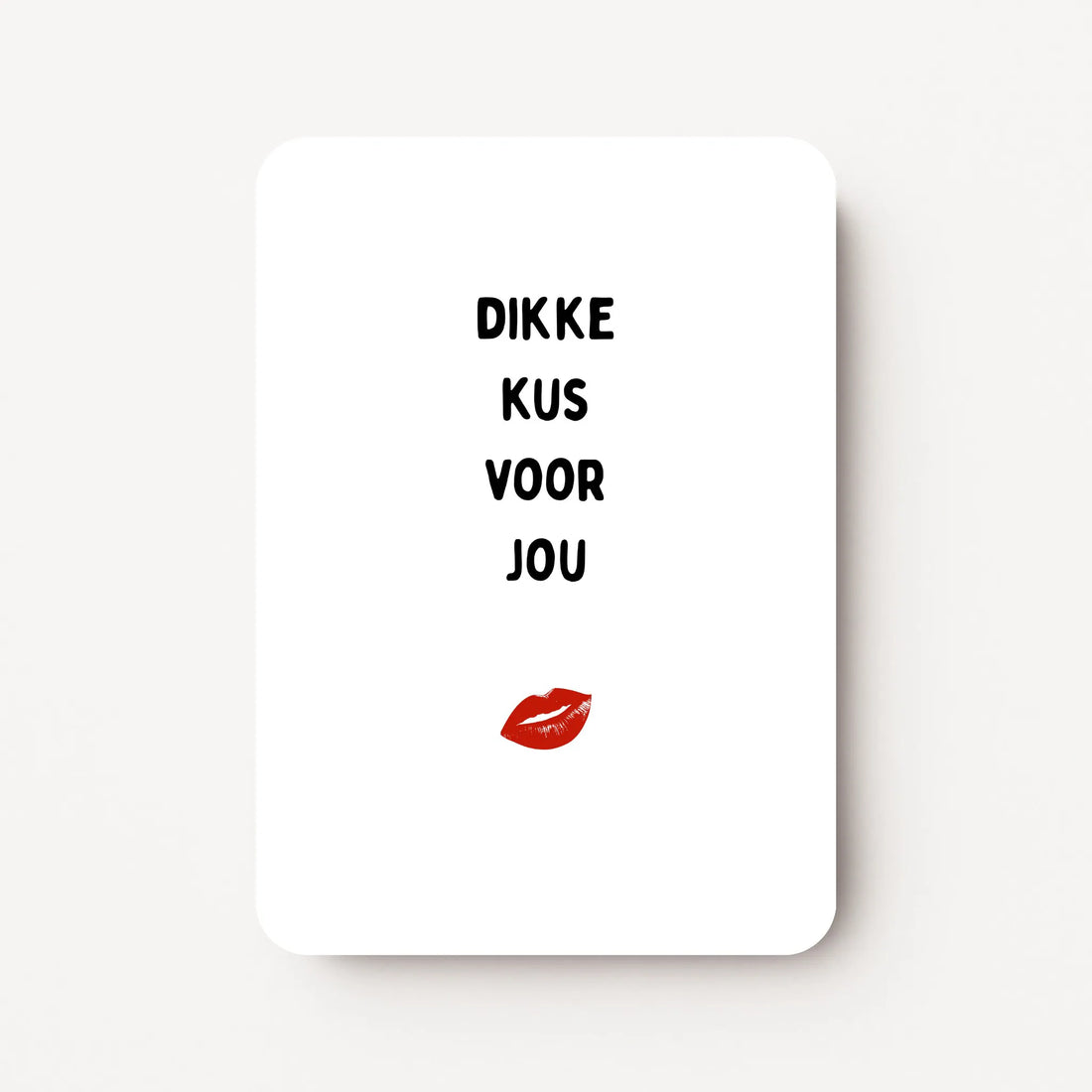 Staande zomaarkaart met zwarte tekst ‘Dikke kus voor jou’ en een illustratie van een mond die een zoen geeft erboven, flatlay op witte ondergrond.