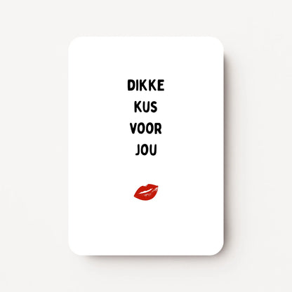 Staande zomaarkaart met zwarte tekst ‘Dikke kus voor jou’ en een illustratie van een mond die een zoen geeft erboven, flatlay op witte ondergrond.