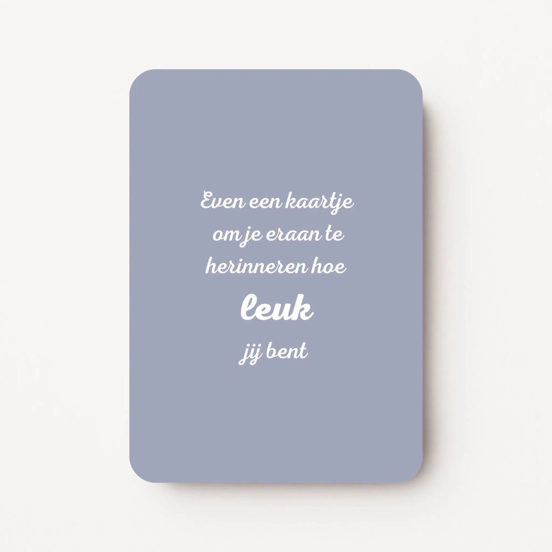 Staande kaart met tekst ‘Een kaartje om je eraan te herinneren hoe leuk je bent’ in witte letters op een warme paarsroze achtergrond, flatlay op witte ondergrond.